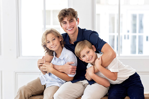 Three brothers sitting together and smiling during a family photography session at The Beverly-Harris House in McKinney, Texas.