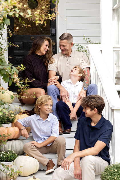 Family of five sitting together on the porch at The Beverly-Harris House in McKinney, Texas during a fall family photography session.