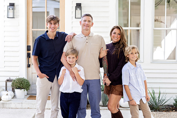 Family of five standing together outside The Beverly-Harris House in McKinney, Texas during a fall portrait session.